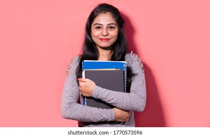 Young pretty female student holding books and file in hand.