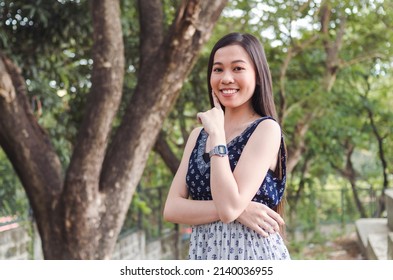 A young pretty Filipina woman in a confident mood. Happy about her glowing and beautiful skin. Outdoor scene at the park.
