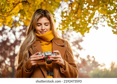 Young pretty girl analog photography enthusiast, taking pictures in the park in autumn   - Powered by Shutterstock