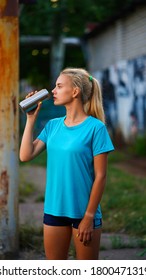 Young pretty girl athlete in blue shirt going to drink water from soda can - Shutterstock ID 1800471319
