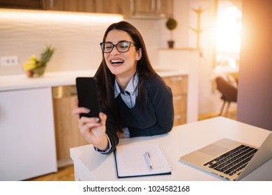 Young pretty girl chatting online. Woman in home office using video chat on mobile.