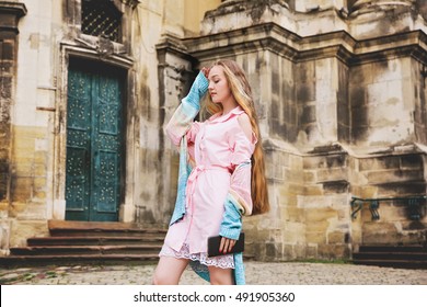 Young Pretty Girl With Extra Long Blonde Hair In Light Pink Dress And Knitted Sweater On The City Streets. Beautiful Fashion Woman Outdoors.