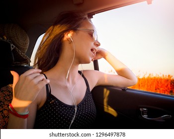 Young Pretty Girl In Headphones Listening To Music And Singing Sitting In Car