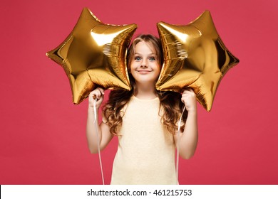 Young pretty girl holding baloons and smiling over pink background.