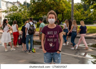 A Young Pretty Girl In Mask Is Standing In A Crowd On A Street, A Lot Of People Walking Without Masks