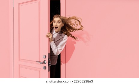 Young pretty girl peeking out open pink door and looking with positive excitement, astonishment. Surprised look. Good news, sales. Concept of emotions, facial expression, lifestyle - Shutterstock ID 2290523863
