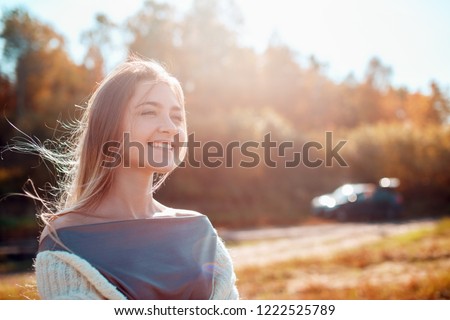 Young pretty girl posing on camera and enjoying sunny autumn day.