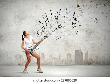 Young pretty girl in shorts and shirt playing imaginary guitar