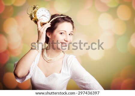 Young pretty girl showing an alarm clock on bokeh background