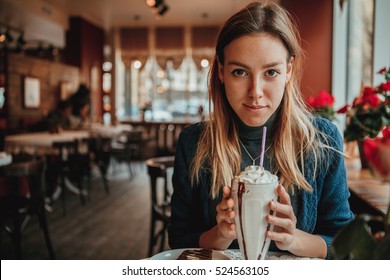 Young pretty girl sitting in comfortable cafe with a milkshake. Waiting for boyfriend. Taking a break. Rest for a minute - Powered by Shutterstock