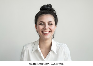 Young pretty girl smiling and looks at the camera on the light background. - Shutterstock ID 695892685