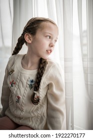 Young Pretty Girl Stuck Indoors Sat On Windowsill Looking Through Curtain Window Outside Into Garden With Cute Pigtails Platted Long Hair On Bright Summer Day Dressed Smart Flowers On Wool Jumper