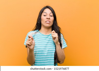 Young Pretty Hispanic Woman Feeling Disgusted And Nauseous, Backing Away From Something Nasty, Smelly Or Stinky, Saying Yuck Against Brown Wall