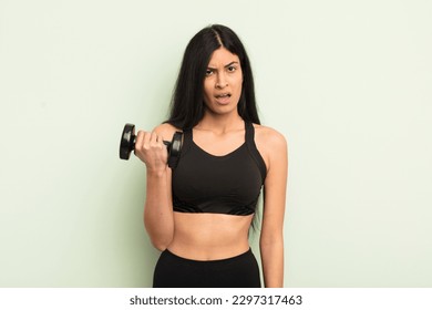 young pretty hispanic woman feeling puzzled and confused. fitness concept