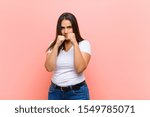 young pretty hispanic woman looking confident, angry, strong and aggressive, with fists ready to fight in boxing position against pink wall