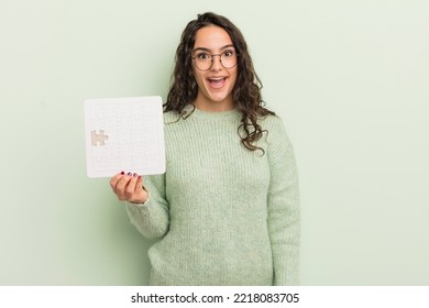 Young Pretty Hispanic Woman Looking Happy And Pleasantly Surprised. Puzzle Concept