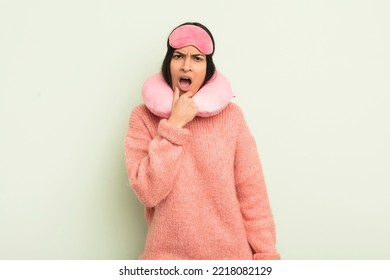 Young Pretty Hispanic Woman With Mouth And Eyes Wide Open And Hand On Chin. Plane Passenger Concept