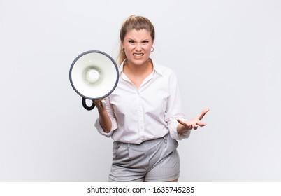 young pretty latin woman looking angry, annoyed and frustrated screaming wtf or what‚Äôs wrong with you with a megaphone against white wall - Shutterstock ID 1635745285
