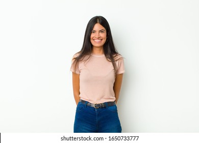 Young Pretty Latin Woman Looking Happy And Goofy With A Broad, Fun, Loony Smile And Eyes Wide Open Against Flat Wall