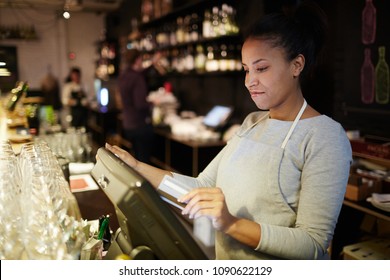 Young Pretty Mixed Race Waitress Standing At Bar Counter And Processing Order Of Customer In POS System