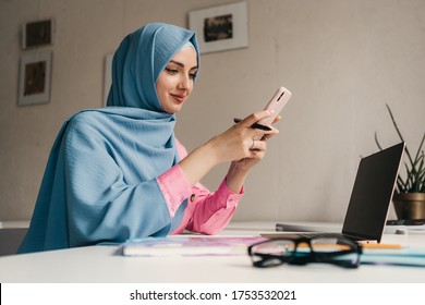 Young Pretty Modern Muslim Woman In Hijab Working On Laptop In Office Room, Education Online, Remote Work Freelancer, Using Smatphone Thinking