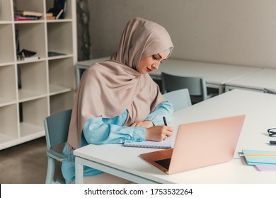 Young Pretty Modern Muslim Woman In Hijab Working On Laptop In Office Room, Education Online, Remote Work Freelancer, Making Notes Thinking