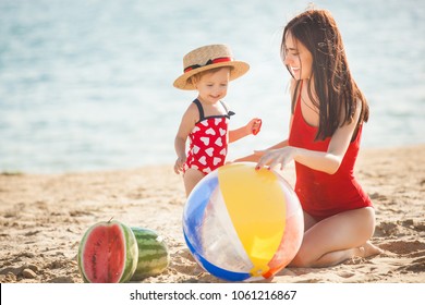 Young pretty mother playing with her little cute daughter at the beach. Loving mom having fun with her child at the sea shore - Powered by Shutterstock