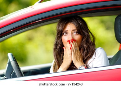 Young pretty scared woman sitting in the red car