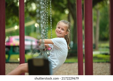 Young Pretty Smiling Teenage Girl Playing Alone On Swings On Summer Playground