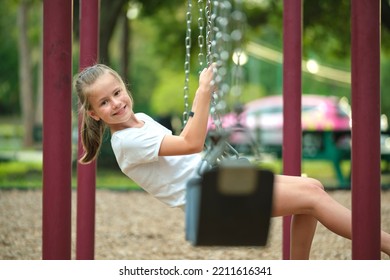 Young Pretty Smiling Teenage Girl Playing Alone On Swings On Summer Playground