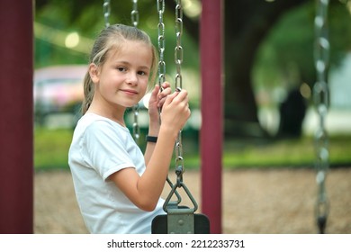 Young Pretty Smiling Teenage Girl Playing Alone On Swings On Summer Playground