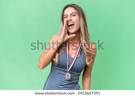Young pretty sport Uruguayan woman with medals over isolated background shouting with mouth wide open