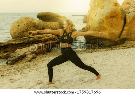Young pretty sport woman in sportswear practicing asana exercise on the sand at the wild beach. Outdoor yoga training