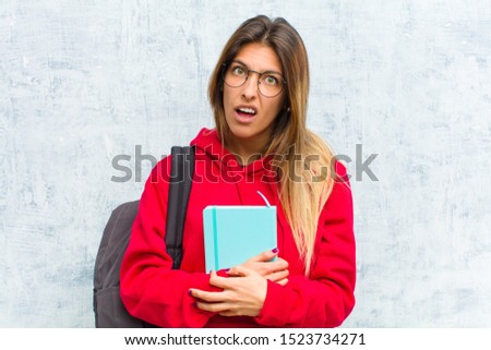 young pretty student feeling puzzled and confused, with a dumb, stunned expression looking at something unexpected
