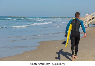 Young pretty surfer with wet suit boy holding yellow surfboard on the beach from behind. - Powered by Shutterstock