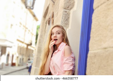 Young Pretty Surprised Girl With Extra Long Blonde Hair In Light Pink Dress On The City Streets. Beautiful Shocked Woman Outdoors.