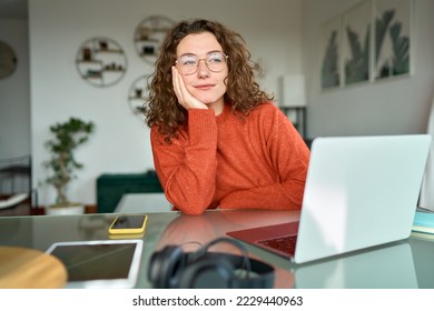 Young pretty thoughtful woman student looking away thinking while working learning online on laptop computer at home taking break feeling bored, dreaming or contemplating, reflecting sitting at table. - Powered by Shutterstock