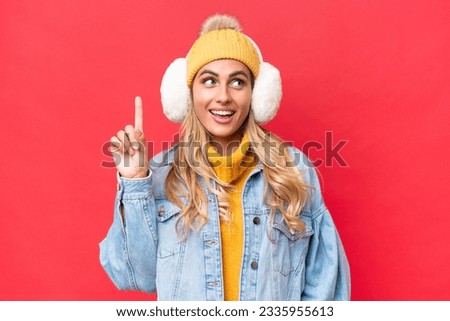 Young pretty Uruguayan woman wearing winter muffs isolated on red background background intending to realizes the solution while lifting a finger up