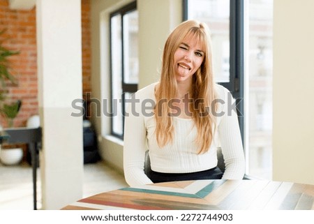young pretty woman with cheerful, carefree, rebellious attitude, joking and sticking tongue out, having fun. home interior