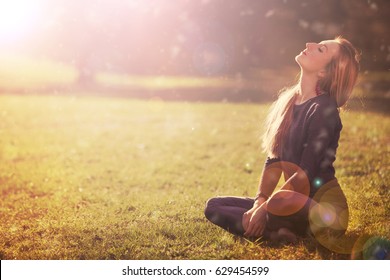 Young pretty woman with closed eyes basks in sun in forest.  Spring. Glow Sun, Sunshine. Backlit. Toned in warm colors  - Shutterstock ID 629454599