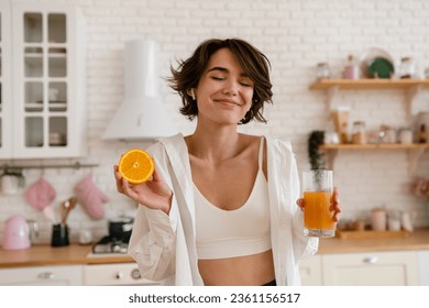 young pretty woman cooking at home, morning kitchen, healthy food, cutting fruits oranges, making orange juice - Powered by Shutterstock