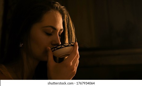 Young pretty woman drinking hot tea. Warm romantic illumination, low key. Chinese tea ceremony and relaxation concept