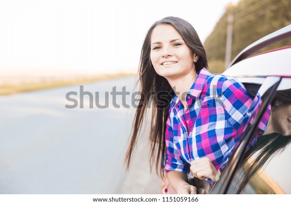 Young pretty woman driving car\
and leaning out of car window. traveling by car, summer\
holidays