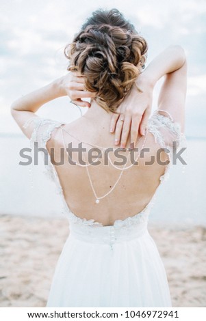 Young pretty woman in elegant dress. Back view wedding fashion background.