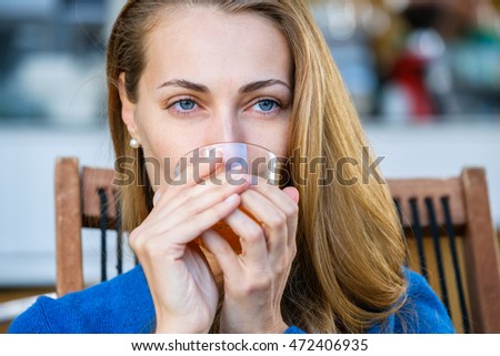 Young pretty woman enjoys cup of tea in outdoor cafe