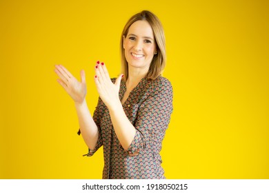 Young Pretty Woman Feeling Happy And Successful, Smiling And Clapping Hands, Saying Congratulations With An Applause Over Yellow Background.