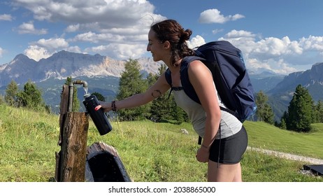 Young Pretty Woman Filling Her Water Bottle, In The Dolomites