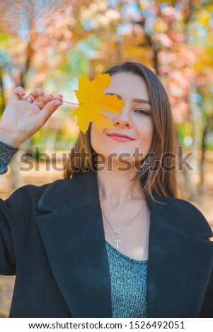 young pretty woman fooling around with yellow maple leaf