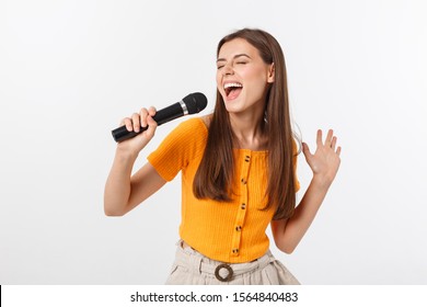Young pretty woman happy and motivated, singing a song with a microphone, presenting an event or having a party, enjoy the moment - Shutterstock ID 1564840483