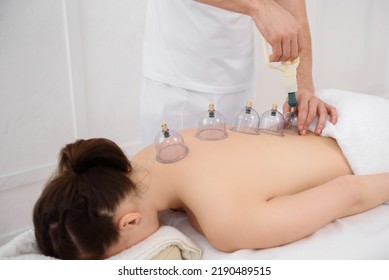 Young pretty woman having back massage with vacuum cups in spa, white background. Copy space, closeup - Shutterstock ID 2190489515